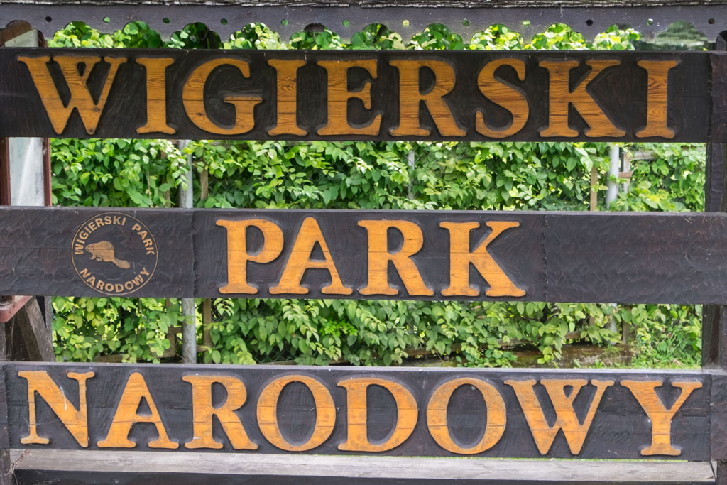 Znak informacyjny Wigierski Park Narodowy z bobrem w logo parku.