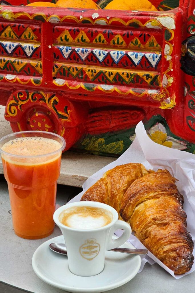 Śniadaniowy zestaw - świeży sok, kawa i rogalik.