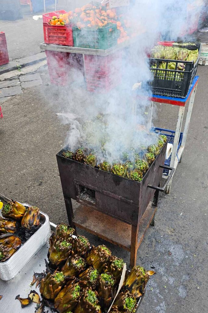 Grilowanie karczochów na rynku w Katatnii.