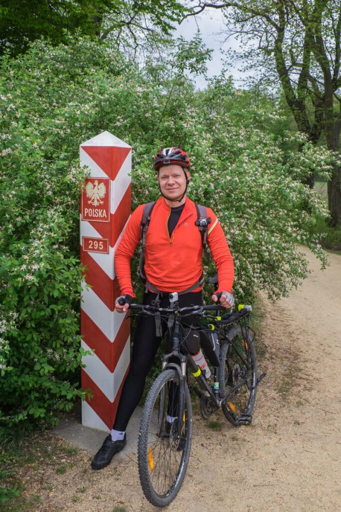 Tomek na tle znaku granicznego z Niemcami na Nysie Łużyckiej.